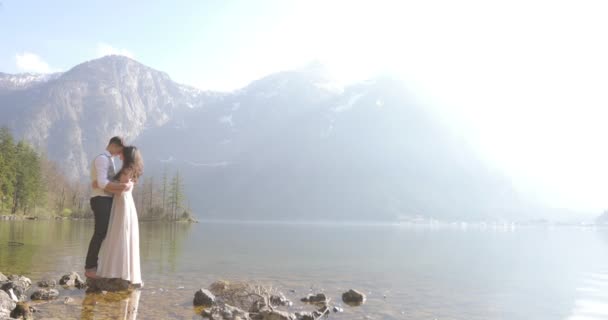 Horizontale weergave van het charmante gelukkige paar knuffelen in de buurt van de rivier op de achtergrond van de bergen. — Stockvideo