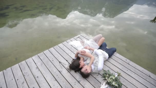 Composición romántica de dos amantes de los besos tendidos en el muelle cerca del ramo durante sus vacaciones en las montañas . — Vídeo de stock