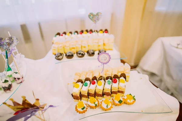 Dessert réception de mariage. Délicieux morceaux de gâteaux sur la table avec le panneau de buffet de bonbons . — Photo