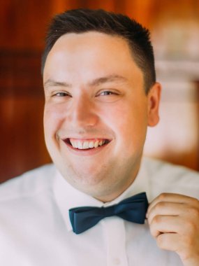 Neşeli Damat Düğün mavi papyon düzeltir. Yakın çekim portre.