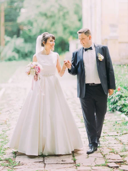 Feliz casal recém-casado encantador está andando ao longo da rua . — Fotografia de Stock