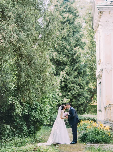 Beijar casal recém-casado está passando tempo no jardim florescendo . — Fotografia de Stock