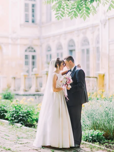 Mutlu sarılma yeni evliler sokakta kafa kafaya ayakta iken düğün buket tutuyorsun.