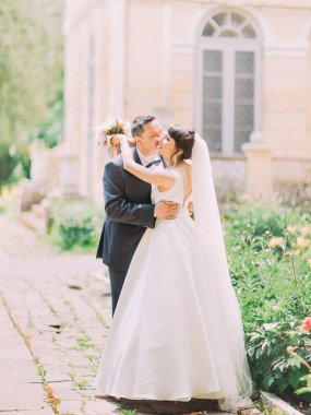 Yakışıklı damat gelin yanak içinde öpüşme tam uzunlukta fotoğraf. Sokak konumu.