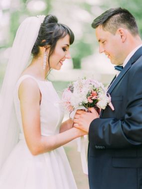 Varoluş yan portre peonies düğün buket tutan gülümseyen yeni evli çiftin.