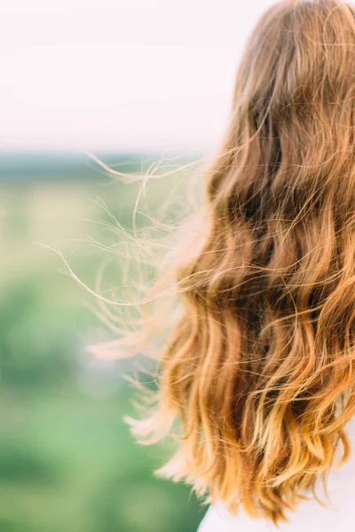 O cabelo encaracolado loiro longo da noiva nas montanhas verdes borradas. Foto vertical . — Fotografia de Stock