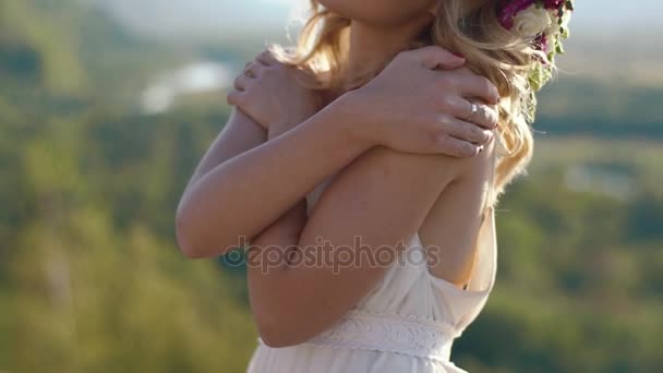 Das romantische Porträt der schönen Frau im weißen Kleid und mit dem Blumenkranz auf dem Kopf in den Bergen — Stockvideo