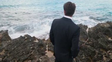 Dalgaları seyretmekten kayalık sahil üzerinde siyah klasik ceket şık damat. Kıbrıs Düğün