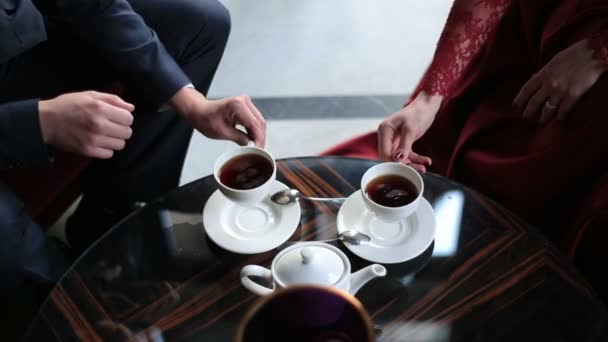 Vista superior de las manos de la pareja bebiendo té y poniendo tazas en su lugar. Ubicación del café . — Vídeos de Stock