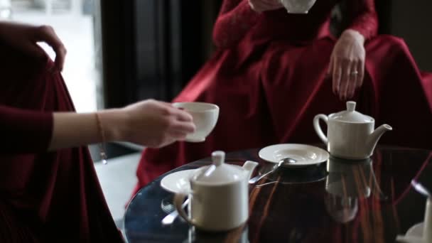 Vista de cerca de las manos de dos mujeres en té rojo en la cafetería . — Vídeos de Stock