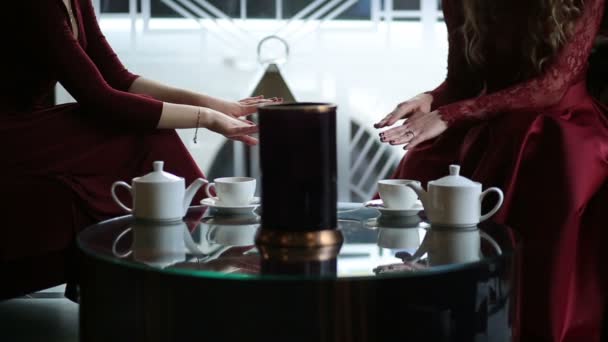 Las manos ven a las mujeres en rojo. Las chicas se están mostrando las joyas mientras están sentadas en el café. . — Vídeos de Stock