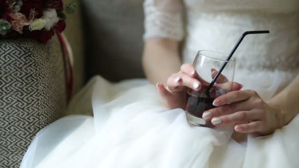 Προβολή με μεγέθυνση από τα χέρια της νύφης με μανικιούρ κρατώντας το ποτήρι με κόκκινο ποτό ενώ κάθεται στο καφενείο. — Αρχείο Βίντεο