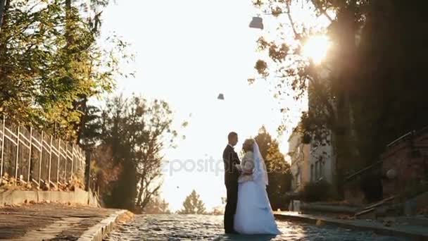 Recém-casados beijam abraçando uns aos outros concurso na rua cheia de sol — Vídeo de Stock