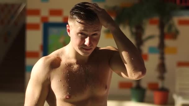 若い美しい裸胸男ホテル プールのそばでリラックスできます。彼の体を流れる水の滴。男の頭部に彼の手を取って、髪で遊んで. — ストック動画