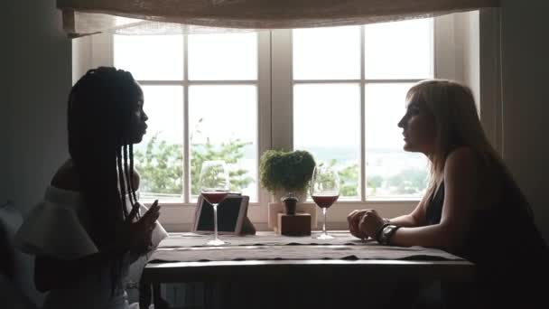 Two women drinking wine from wineglasses on informal meeting in resturant. Focus on blonde woman — Stock Video