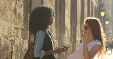 İki sevimli çok kültürlü öğrenci güneşli sokakta konuşma.