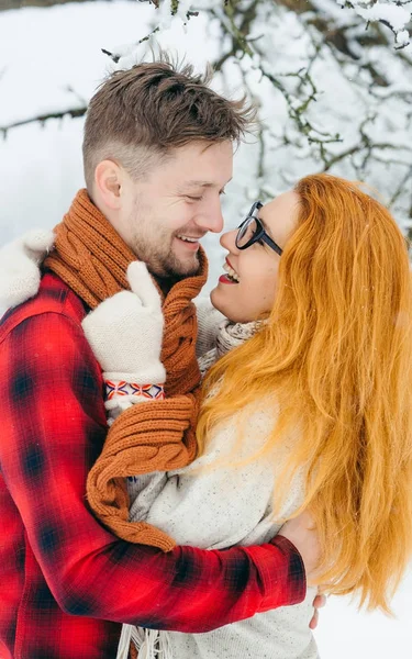 Vertikales halblanges Porträt des glücklich lächelnden Paares, das sich im verschneiten Wald umarmt. — Stockfoto