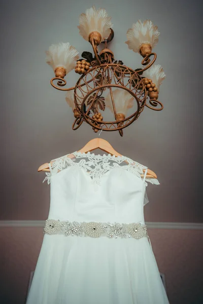 La vista hacia arriba en el hermoso vestido de novia con decoraciones que entregan en la lámpara de araña. Disparo vertical . —  Fotos de Stock