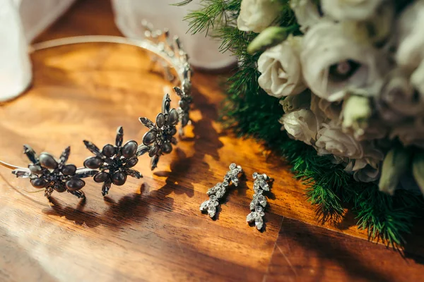 Composición de la boda que consta de pendientes largos de plata con diamantes, aro de pelo con flores de hierro y ramo de rosas blancas en el suelo . —  Fotos de Stock