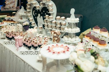 Çikolata paketiyle farklı lezzetli kekler, macarons, şeker ve diğer tatlılar düğün için. Pembe ve beyaz kompozisyon. Yan görünüm.