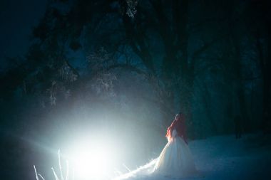Güzel gelin tam uzunlukta görünümünü atkı örgü ve gece karlı orman Beyaz ışığa yakın duran kırmızı kaplı.