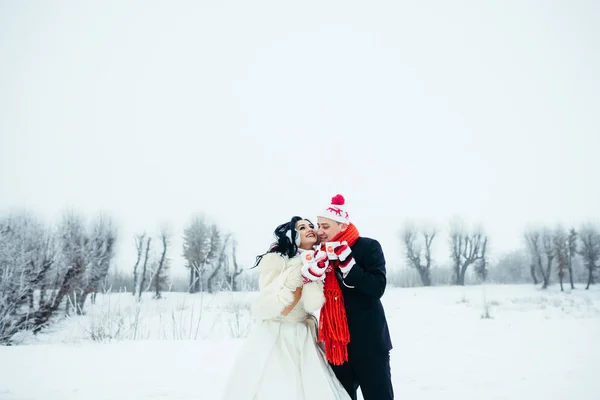 Ευτυχισμένη χαρούμενη νεόνυμφους ζευγάρι αγάπη φορώντας αστεία καπέλα γάντια Close-up πορτρέτο Φλυτζάνια καφέ τσάι γάμου χειμώνα χιονισμένο οριζόντια. — Φωτογραφία Αρχείου