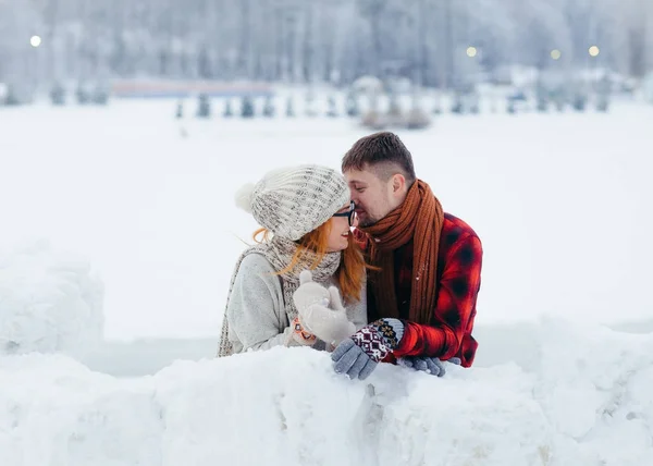 El hombre guapo está susurrando algo gracioso en el oído de su novia riendo. Ubicación del pueblo de invierno . — Foto de Stock
