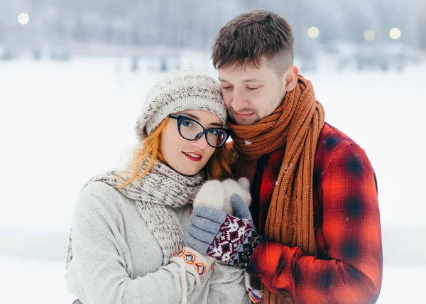 Retrato ao ar livre de inverno do casal abraço bonito feliz. O homem está aquecendo as mãos de sua namorada . — Fotografia de Stock