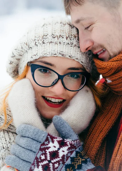 O homem bonito está suavemente abraçando sua linda garota de cabelo sorridente com óculos. Close-up vertical ao ar livre retrato de inverno . — Fotografia de Stock