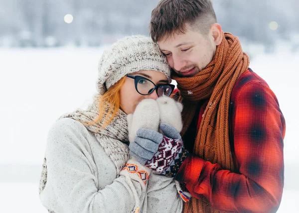 La coppia amorevole che abbraccia. Una donna attraente con gli occhiali si sta scaldando le mani. Inverno ritratto all'aperto . — Foto Stock