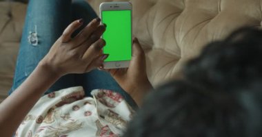 Arkadan Görünüm yakın hiçbir yüz cep telefonu yeşil ekran kanepe yalan sörf Net chat yapan Afro Amerikalı kadın kadar sakin ol 4k.