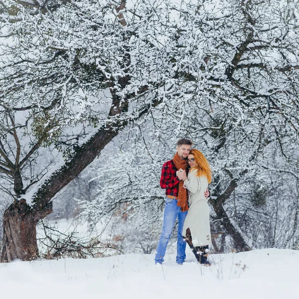 Vista completa de la feliz pareja amorosa abrazándose durante su paseo por el bosque nevado . — Foto de Stock