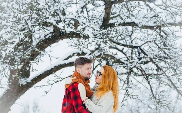 Halblanges Porträt des verliebten Paares. die schöne rothaarige Frau umarmt ihren hübschen Liebhaber im verschneiten Wald. — Stockfoto