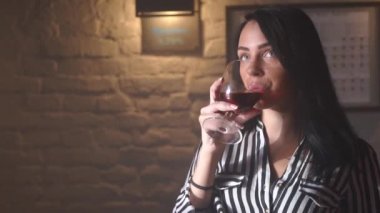 Siyah uzun saçlı koyu geyik içme ve barda Tv izlerken gülümseyen kadın yakın çekim portresi.