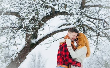Yakın çekim yatay dikey mutlu çift yüzleri kar yağışı orman kabarık kar aşk duyarlı dokunmadan sarılma.
