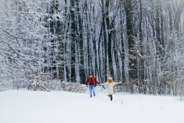 Çift gülümseyen sevgi dolu karlı orman çalışırken eğleniyor. Tam uzunlukta görünümü. Noel zamanı.