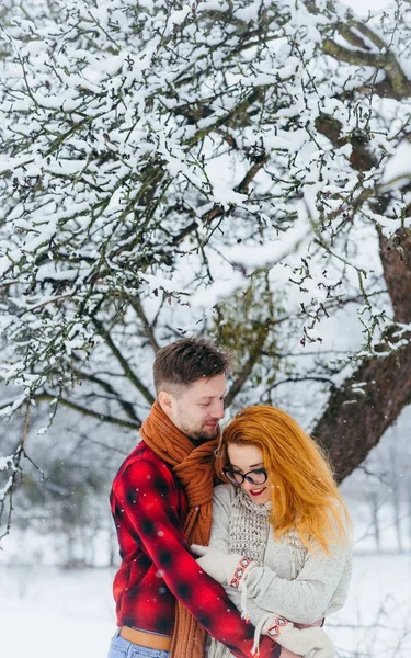 Retrato vertical de meio comprimento do belo e alegre casal abraçando na floresta nevada . — Fotografia de Stock