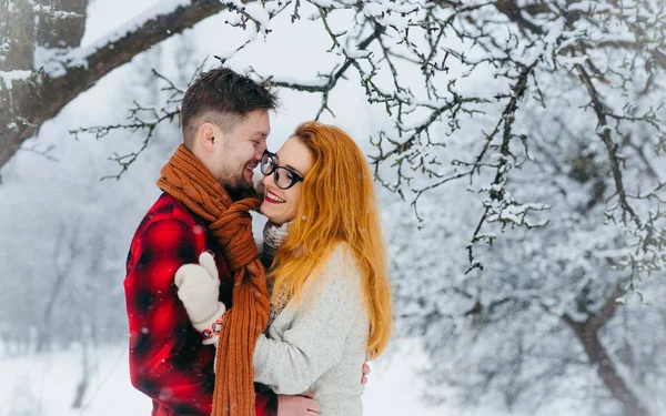 Abrazar a una pareja amorosa es reír durante la nevada en el bosque. Retrato de medio cuerpo . — Foto de Stock