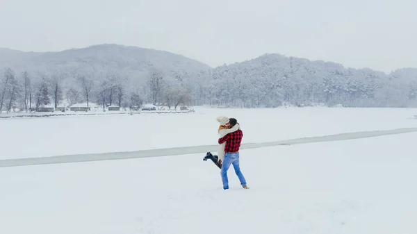 Gasto de tempo alegre de dois belos jovens amantes na floresta de inverno coberta de neve fofa. O homem está girando em torno da encantadora mulher cabeça vermelha . — Fotografia de Stock