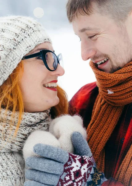 Ritratto ravvicinato della coppia sorridente allegra che si tiene per mano durante tempo invernale. Bella rossa donna sta svezzando gli occhiali . — Foto Stock