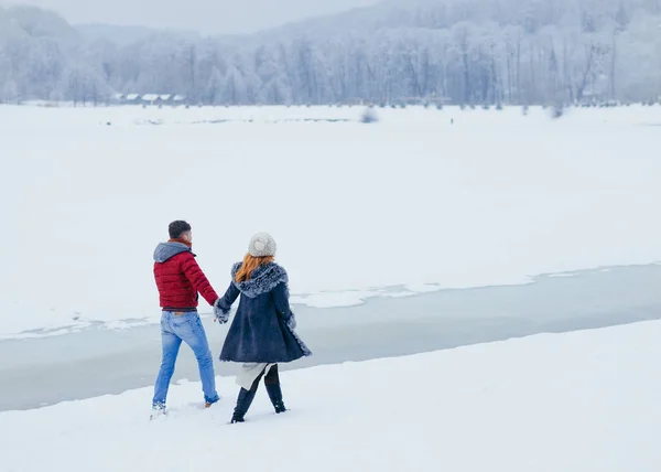 神秘的步行两个恋人沿着草地覆盖着雪。后视图. — 图库照片