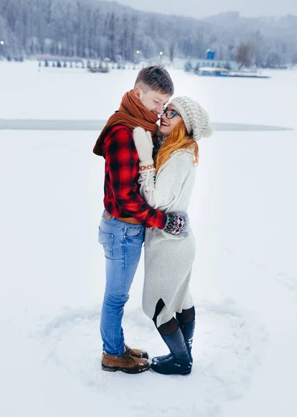 Full-length side shot of the laughing couple of lovers hugging on the snowy meadow. — Stock Photo, Image