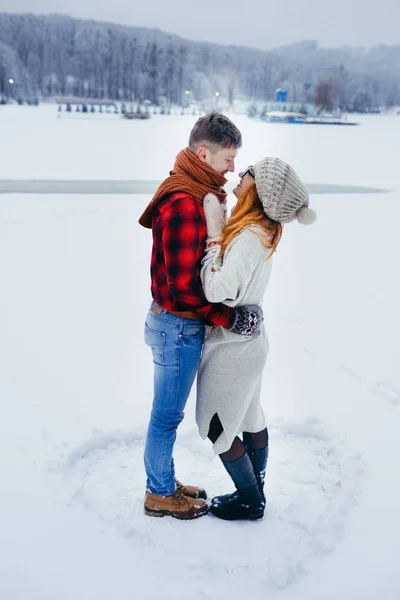 Ευαίσθητα εξωτερική full-length πυροβολισμό. Όμορφο νεαρό ζευγάρι χαμογελαστός και αγκάλιασμα στο φόντο της υπαίθρου που καλύπτονται με χιόνι. — Φωτογραφία Αρχείου