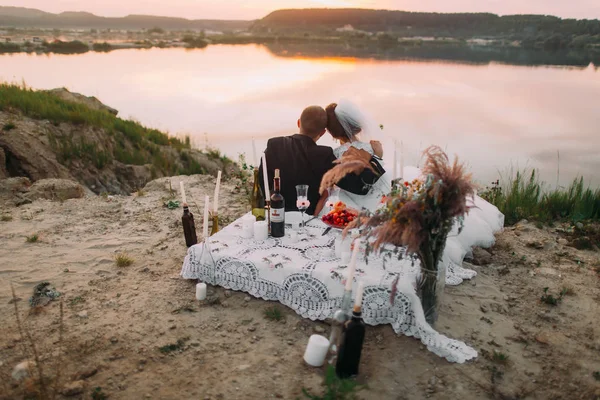 Piknik set arkasında gün batımını izlemek sarılma yeni evliler yatay geri romantik portresi.
