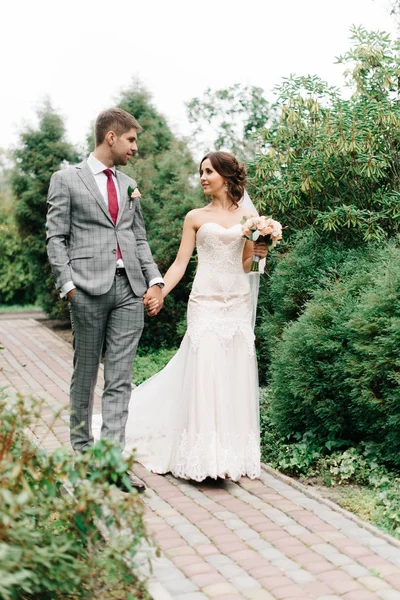 Pequeños novios en ramo gris caminan por el camino — Foto de Stock