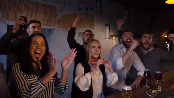 Передний портрет счастливых женщин и мужчин, болеющих за футбольную команду и произносящих тосты за ее победу в баре . — стоковое видео
