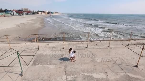 Die obere Ansicht des Mannes, der das Mädchen am Strand im Hintergrund des Meeres dreht. — Stockvideo