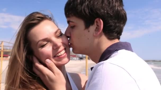 Detailní Portrét muže líbat dívku do tváře na pozadí moře. — Stock video