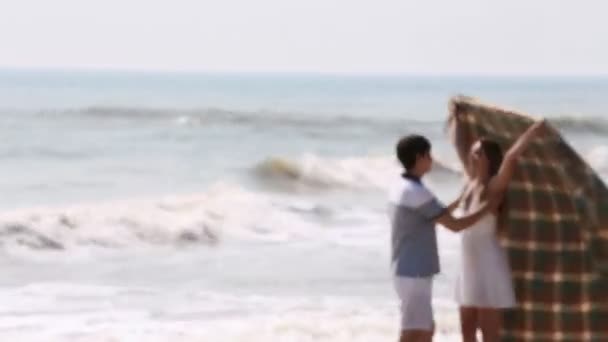 Прекрасный портрет целующейся пары на фоне моря. Женщина заворачивает их в вязаную клетку . — стоковое видео