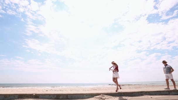 La vista lateral oif la mujer que va en tacones altos mientras que el hombre la está siguiendo. La composición del mar . — Vídeos de Stock